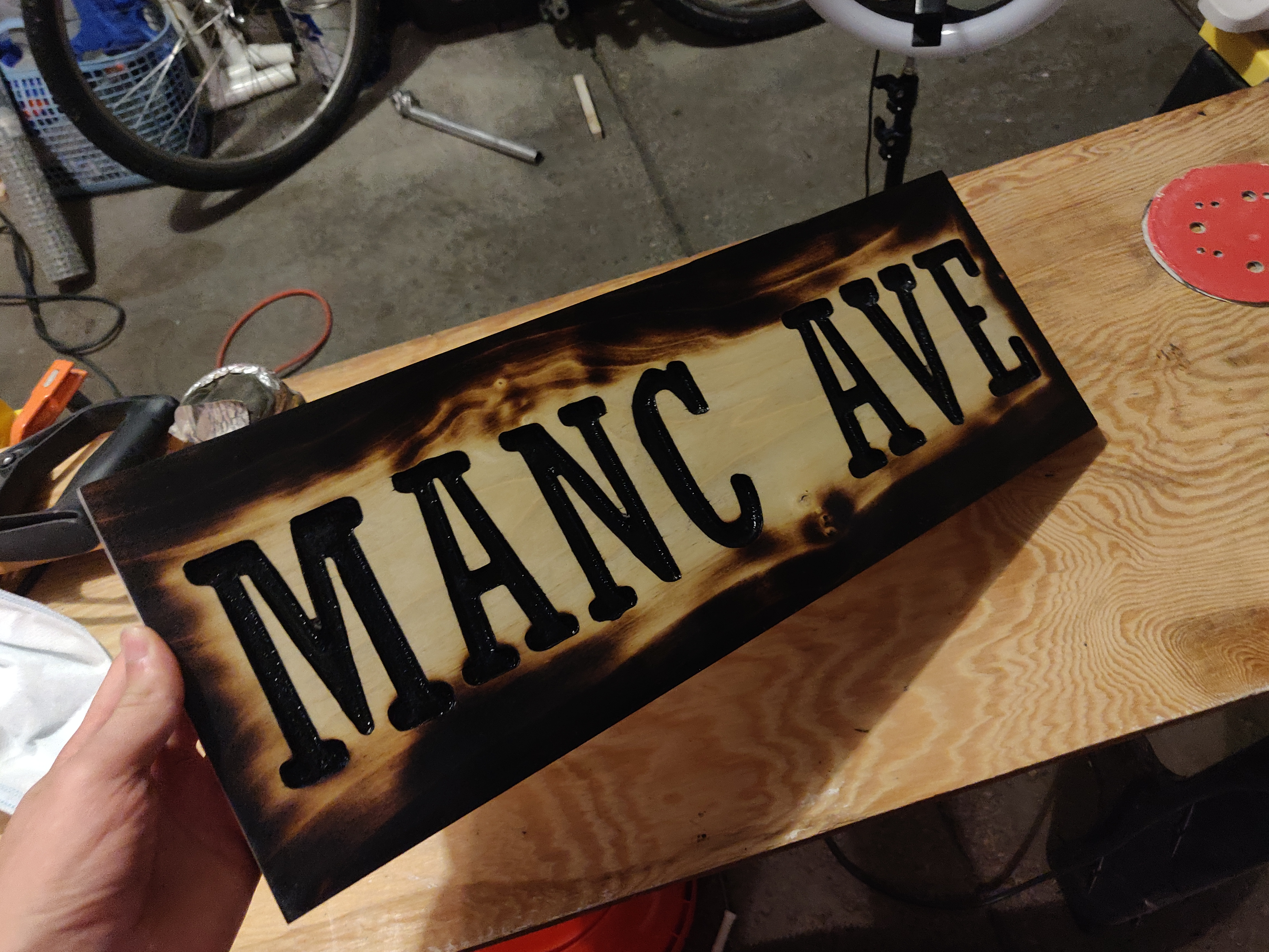 wooden sign with charred edges around letters